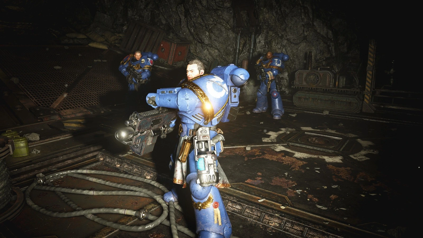 Metalik ve karanlık bir ortamda mavi zırh giymiş üç uzay askeri, silahlarıyla tetikte pozisyon almış halde görülüyor. En öndeki karakter güçlü bir enerji tüfeği taşıyor.